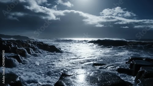Moonlit stormy coastal rocks with crashing waves under a dramatic cloudy sky