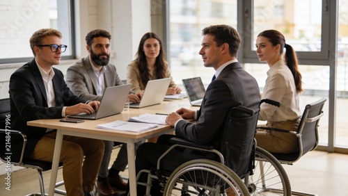 Disabled male manager in wheelchair collaborating with colleagues during business meeting in modern office.