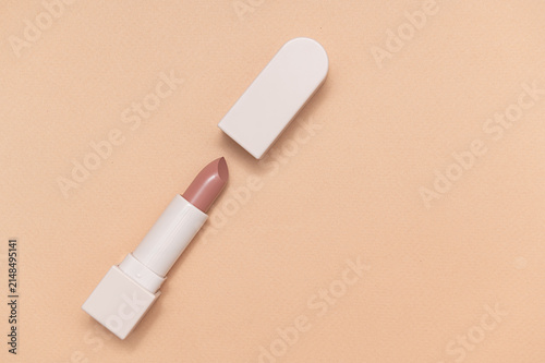 Beige lipstick in a beige container on a beige background. Space for text.