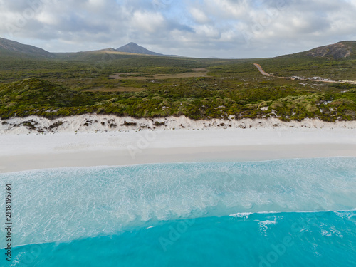 Aerial view of Hellfire Bay featuring pristine white sand, turquoise ocean waves, and coastal scrubland in Cape Le Grand National Park, Western Australia, Australia.
