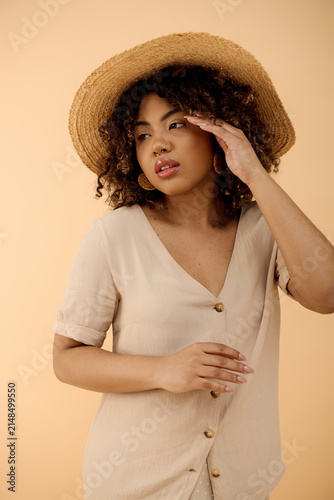 Konstfotografi Young african american woman with beautiful curls wearing a straw hat