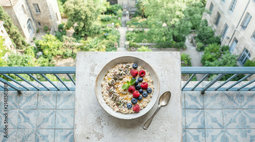 Overhead breakfast bowl with berries and mint on tiled balcony overlooking courtyard