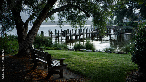 Scenic waterfront view with bench and wooden dock at dusk. Benches facing water near boat dock