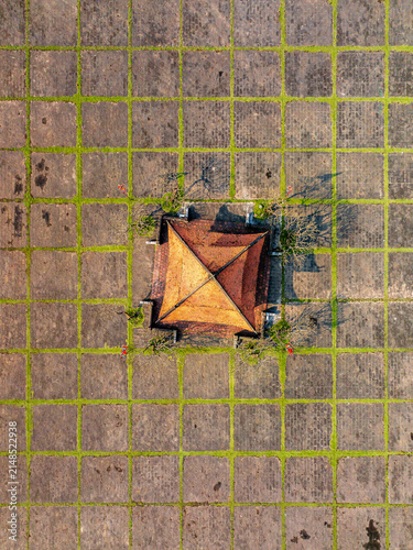 Aerial view of a traditional building with a terracotta roof centered in a geometric stone courtyard with grass-filled grid lines in Vietnam.