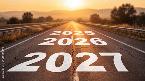 Years 2025, 2026 and 2027 painted on an asphalt highway at sunset