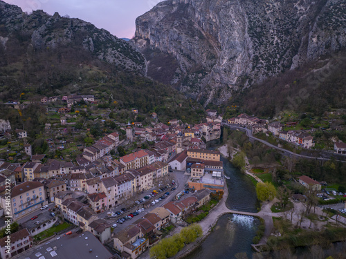 Aerial view of the historic village of Pont-en-Royans with colorful houses perched above the Bourne river, surrounded by limestone cliffs in Pont-en-Royans, Auvergne-Rhone-Alpes, France.