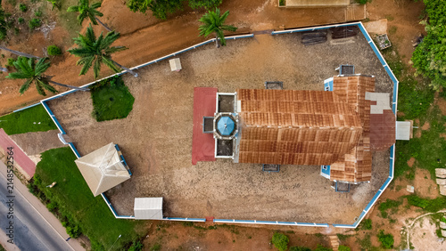 Aerial view of the Presbyterian Church Of Ghana - Bethel Congregation Konongo with its brown roof and blue dome, set in a walled compound with palm trees in Konongo, Ashanti Region, Ghana.