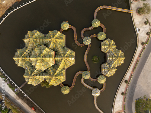 Aerial view of the Pavilion of the Enlightened with its intricate golden roofs and winding walkways surrounded by water in Phraeksa, Samut Prakan, Thailand.