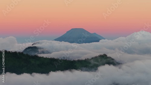 Aerial view of Dieng Plateau mountain peak rising above a sea of clouds at sunset in Kecamatan Batur, Jawa Tengah, Indonesia.