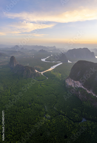 Aerial view of Ao Phang Nga National Park featuring lush mangrove forests, winding river channels, and limestone karsts under a golden sky in Tambon Ko Panyi, Chang Wat Phang-nga, Thailand.