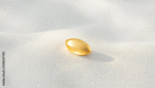 Single golden pill capsule resting on a soft white sand texture with medicine pharmaceutical supplement healthcare treatment wellness nutrition precious abstract minimalist background