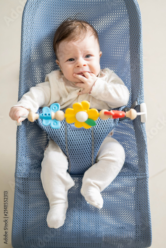 Konstfotografi Portrait of a fussy or crying little baby sitting in a bouncer chair with hands