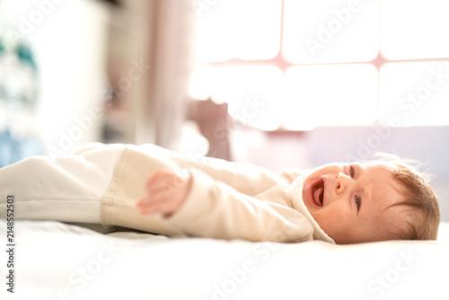 Konstfotografi Portrait of a crying or fussy little newborn baby lying on a bright bed at home