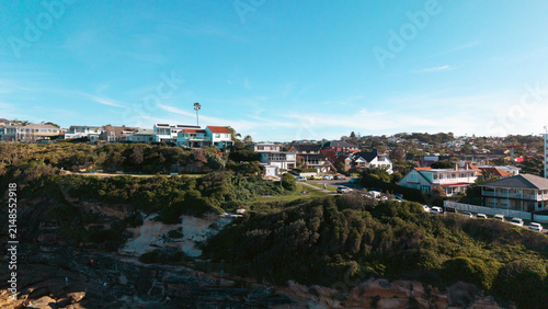 Aerial view of the coastal residential area with houses perched on the hillside overlooking the rocky coastline and lush greenery in Dee Why, New South Wales, Australia.
