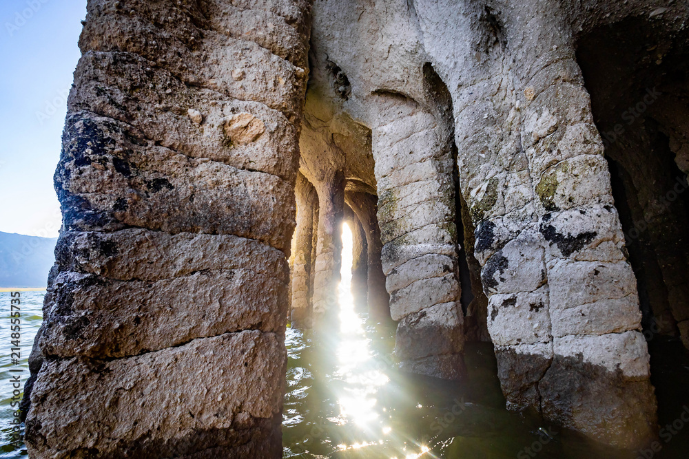 Obraz premium Sunlight filtering through Crowley Lake Stone Columns along shoreline in Mono County California