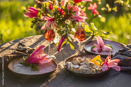 Table setting in garden on sunset light. Table decorated with magnolia flowers under magnolia tree.