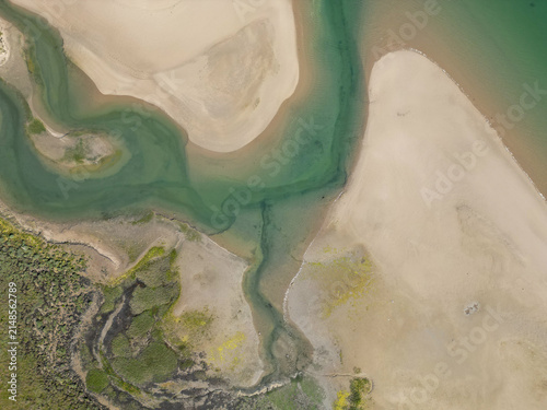 Aerial view of the sandy coastline and tidal estuary channels with clear green water and coastal vegetation in Malahide, County Dublin, Ireland.