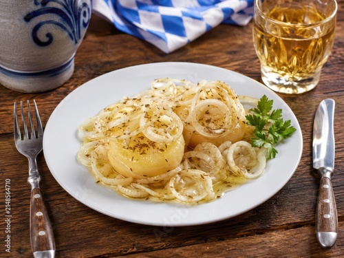 Handkäs mit Musik im deutschen Restaurant: Hessischer Sauermilchkäse mit Zwiebeln, Kümmel, Essig und Öl, klassisch auf weißem Teller mit Apfelwein serviert.