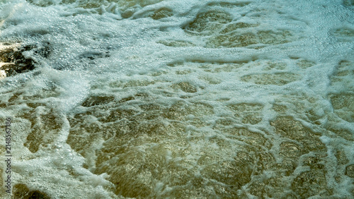 фотографія Waves crash against the rocks at the shore during the afternoon, creating bubble