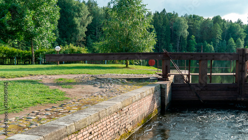 Lock gate by a waterway with trees and grass in a rural landscape during the day