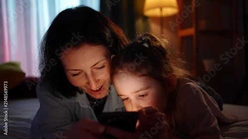 close up joyful mother and a small child use smart phones in the evening,time together