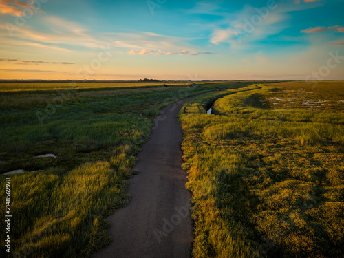 Cuadro en lienzo Aerial view captures coastal pathway and winding lane, Cracked white earth meets green grassland