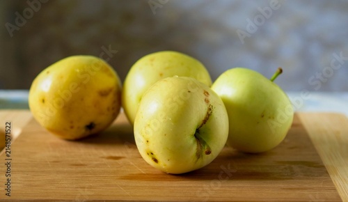 Fotografie Group of Imperfect Organic Yellow Apples on a Wooden Cutting Board