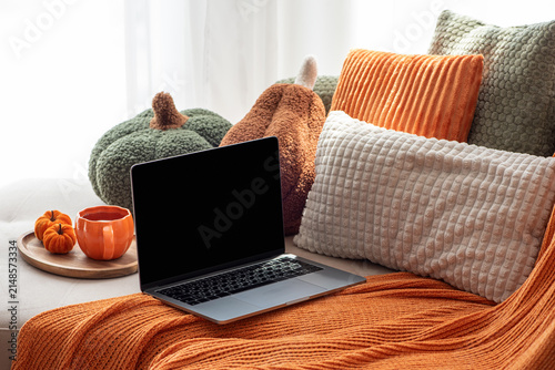 Cozy autumn scene with laptop and pumpkin decor on sofa for seasonal comfort and work from home