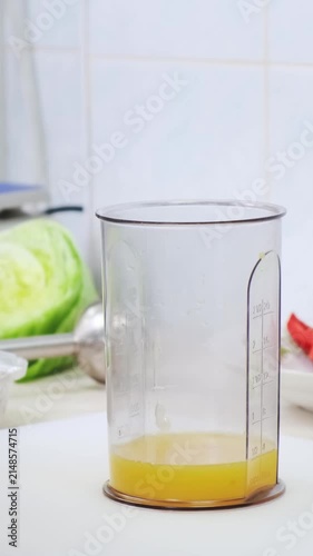 Chef in professional white kitchen make sweet sause with honey and orange juice in blender cup. Cooking, preparing ingredients in restaurant interior. Healthy and diet food delivery concept. 4K shot
