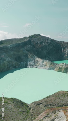 A person stands atop a mountain, gazing at a lake in the Philippines. The scene captures a volcanic crater lake in the distance.