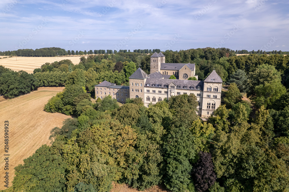 Obraz premium Aerial of abbey and monastery Gerleve Kloster in German hill landscape. Religious monk community building in agriculture scenery seen from above with a blue sky.
