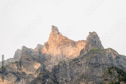 View of the rugged limestone peaks of the Cirque du Fer a Cheval illuminated by golden hour light with steep rock faces and sparse vegetation in Sixt-Fer-a-Cheval, Auvergne-Rhone-Alpes, France.