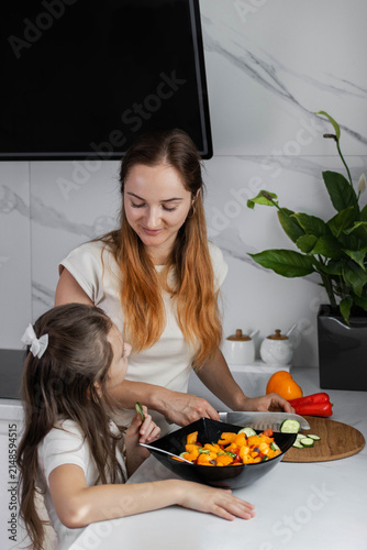 Mother and daughter are preparing a salad. Concept of organic farm products and healthy eating. Happy family.