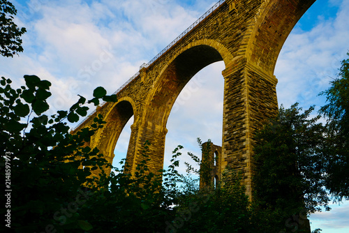 The historic Moorswater Viaduct near Liskeard, Cornwall, spans a deep valley with eight striking semi-circular arches built from snecked rock-faced slatestone and granite. 