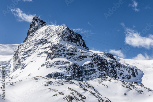 View of the snow-covered Matterhorn peak under a clear blue sky with ski lift cables visible in Zermatt, Valais, Switzerland.