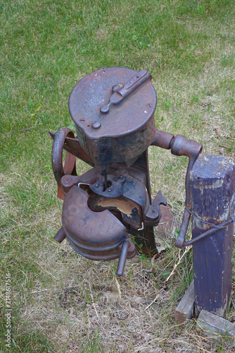 Rusty Antique Cream Separator Attached to Wooden Post on Grassy Lawn, Vintage Cast Iron Mechanism
