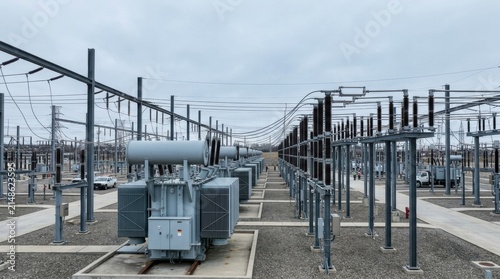 Electrical power substation with large industrial transformer and transmission lines. Infrastructure for energy distribution and high voltage grid system in a power generation facility.