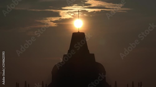 Aerial view of Borobudur Temple silhouetted against a golden sunset sky in Kecamatan Borobudur, Jawa Tengah, Indonesia.