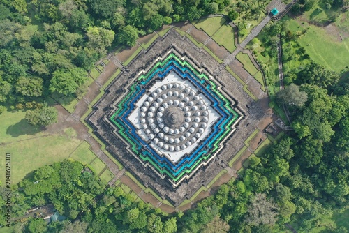Aerial view of Borobudur Temple, a massive Buddhist monument with symmetrical stone stupas surrounded by lush green trees and parkland in Borobudur, Central Java, Indonesia.