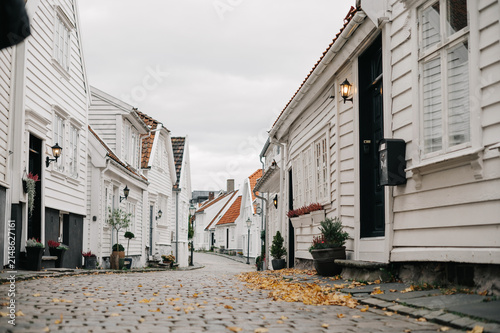 Charming white wooden houses line a cobblestone street in Norway