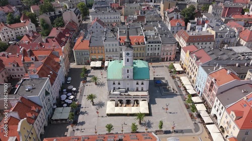 Panoramic aerial drone view of the historic Market Square and Town Hall in Gliwice, Silesia, Poland, featuring colorful tenement houses and red tile roofs on a sunny day.