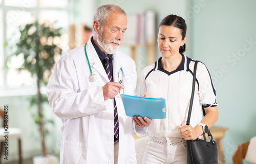 Obraz na płótnie Elderly male doctor sharing positive test results to smiling adult female patien