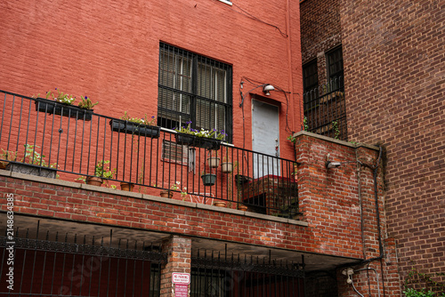 Canvas Print A red brick urban building features a small terrace balcony decorated with potted plants