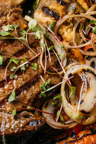 Grilled bone-in steak with vegetables, sauce and microgreens