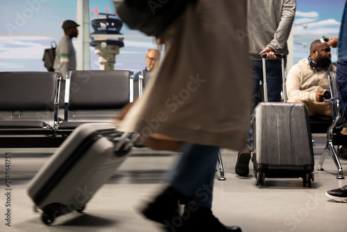Canvastavla Travelers pull luggage trolleys through a busy airport lounge on their way to a departure gate, carrying baggage and preparing to board a plane for a holiday trip and international journey