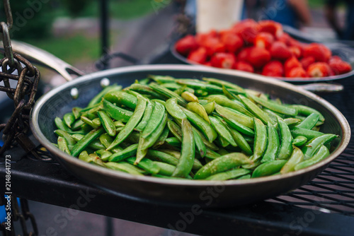 Beans cooking in a pan with a pan of tomatoes cooking in the background