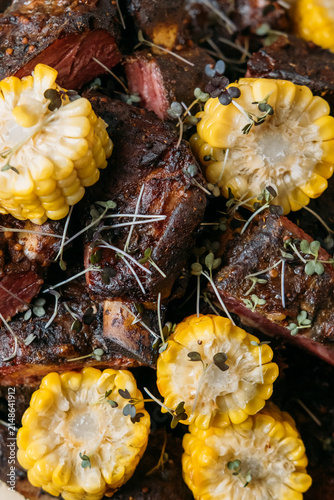 Foto Barbecue beef ribs with corn on the cob and microgreens
