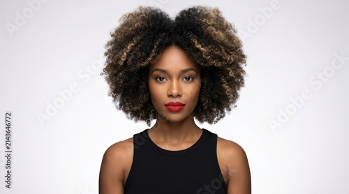 Portrait of a young Black woman with a large afro hairstyle on a white background.