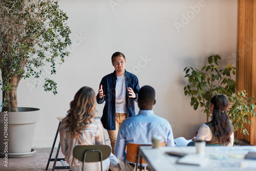 Foto Young male speaker giving a business presentation during a team meeting in a mod