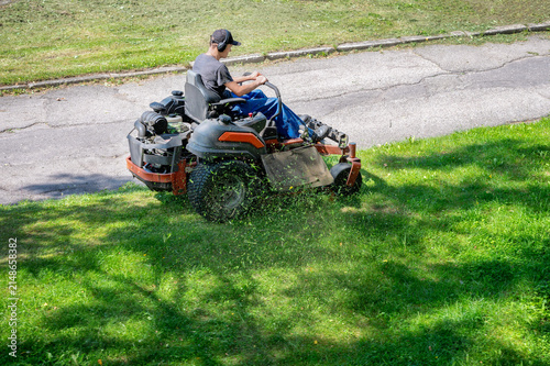 Quadro su tela Man riding professional zero turn lawn mower machine cutting green grass in park